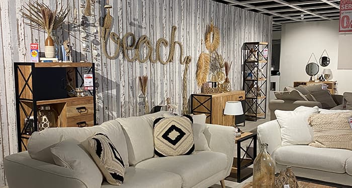 Eine Strandhaus-Koje mit weißen Polstermöbeln und dem Schriftzug 'Beach' im Hintergrund