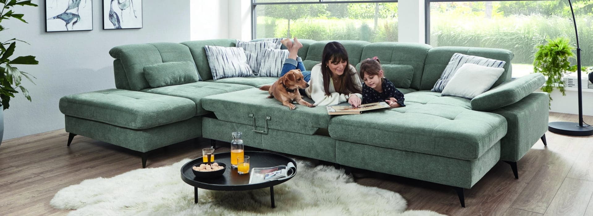 Familie auf einem grünen Sofa im hellen Wohnzimmer