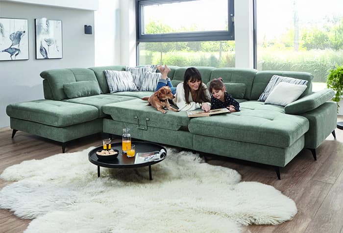 Familie auf einem grünen Sofa im hellen Wohnzimmer