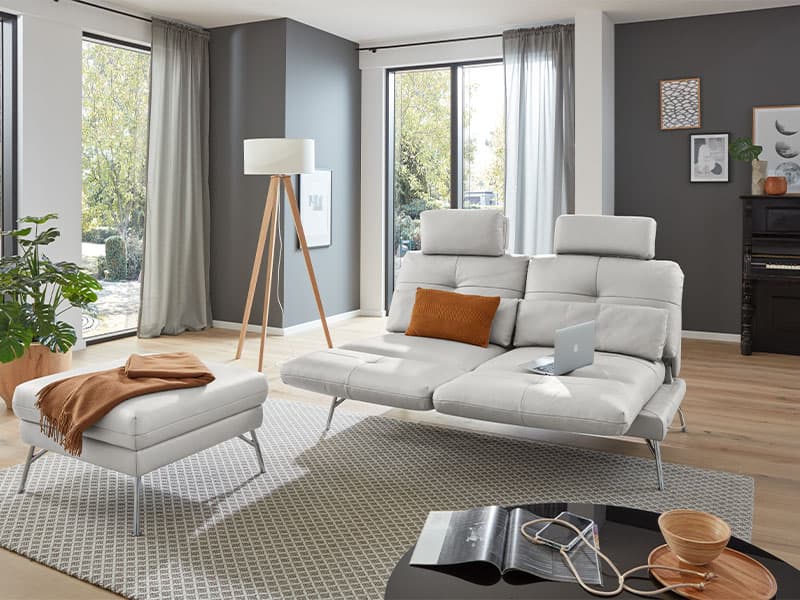 Ein weißes Leder Sofa befindet sich neben einer großen Stehlampe in einem Wohnzimmer