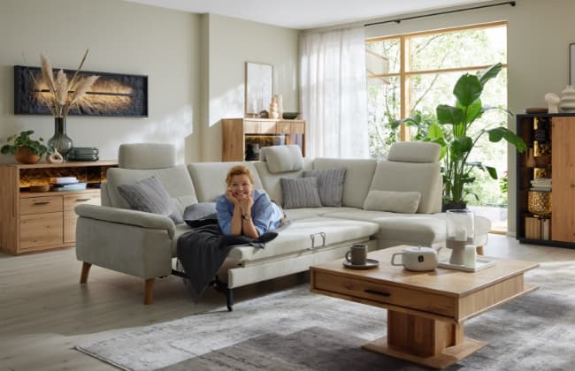 Annette Frier liegt auf einem ausgezogenen Sofa in einem hellen Raum