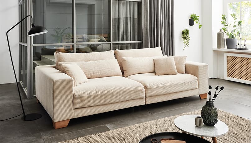 Ein weißes Sofa mit Holzfüßen.