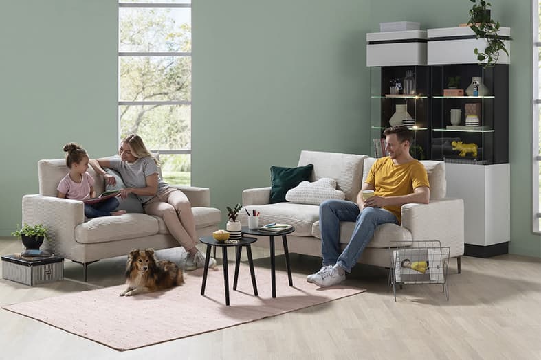 Ein Vater, eine Mutter und deren Tochter sitzen auf einem hellen Cord-Sofa von Opti-Living.