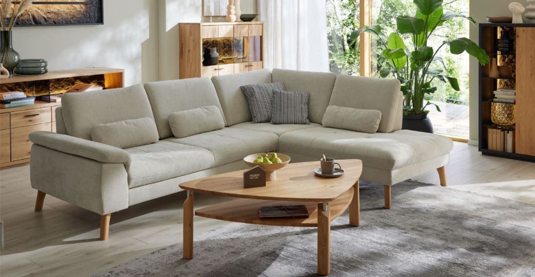 Ein helles Wohnzimmer mit beiger Couch und Holzmöbeln