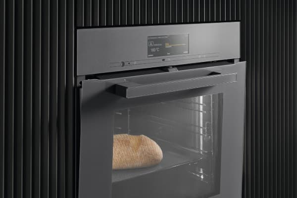 Geöffneter schwarzer Einbaubackofen mit digitaler Anzeige bei 180 °C und einem Brot im Garraum.